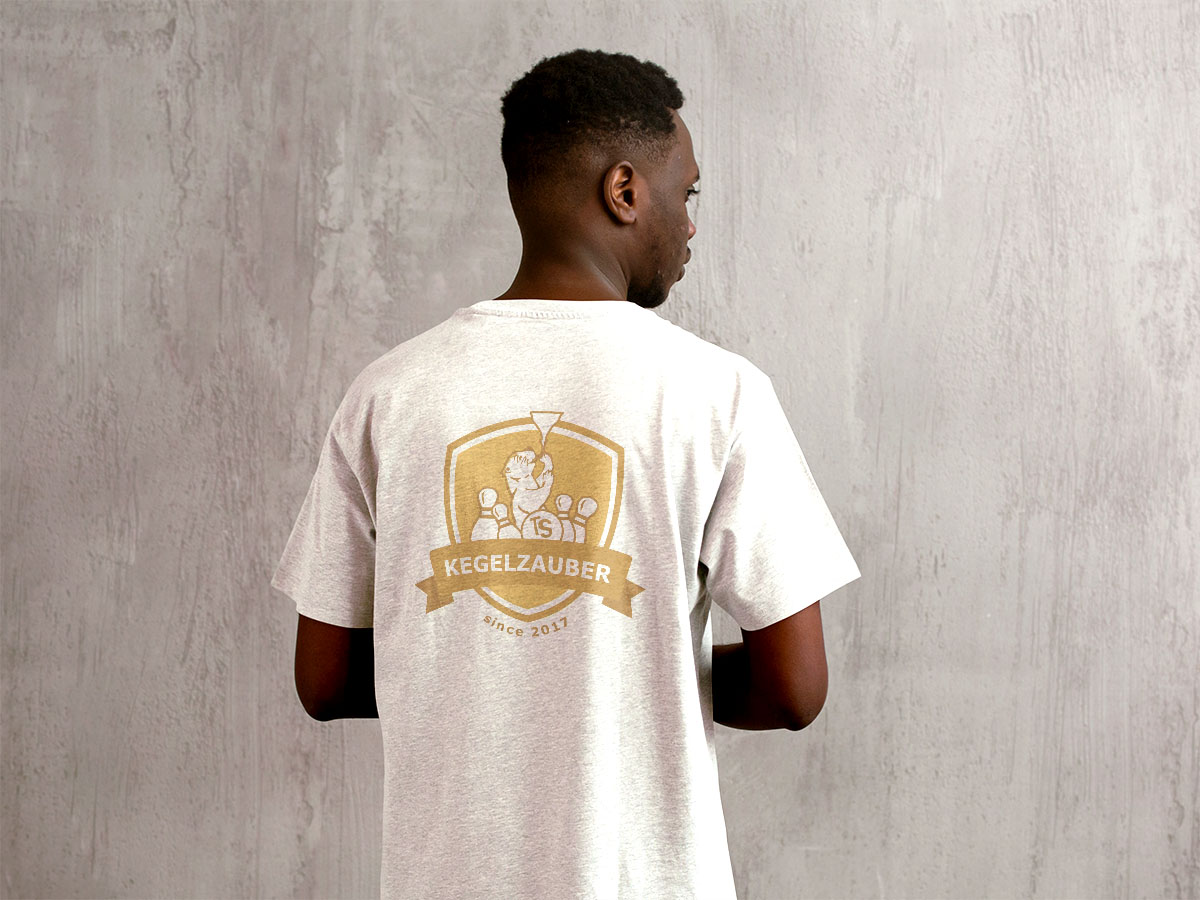 Éin Mann ist von hinten zu sehen und trägt eine weißes T-shirt. Das Logo ist groß auf den Rücken gedruckt